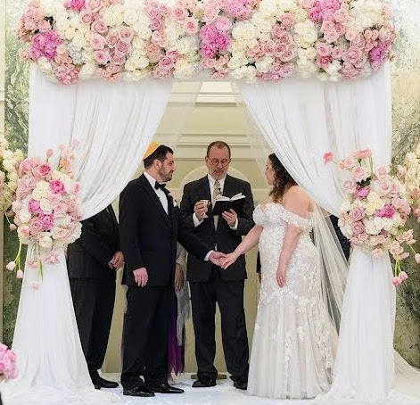 A couple under a chuppah covered in flowers